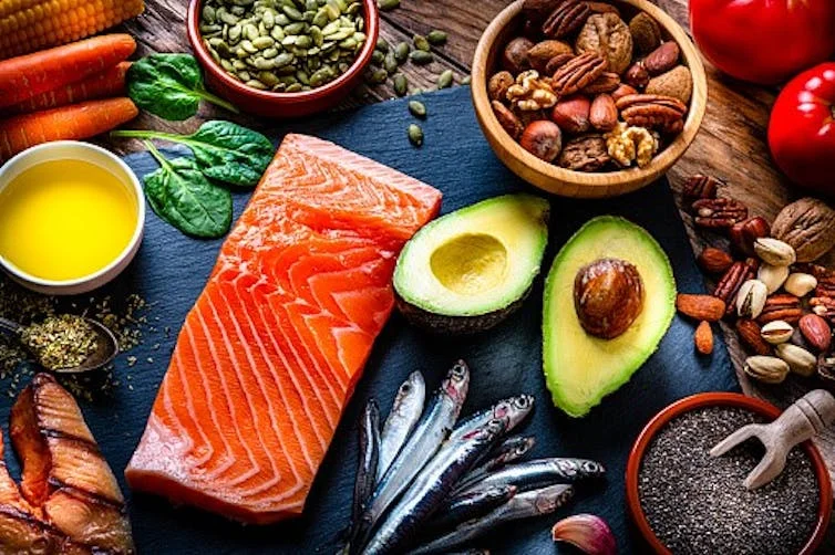 A display of foods rich in omega-3 fatty acids, including salmon, avocado and a variety of nuts and seeds.