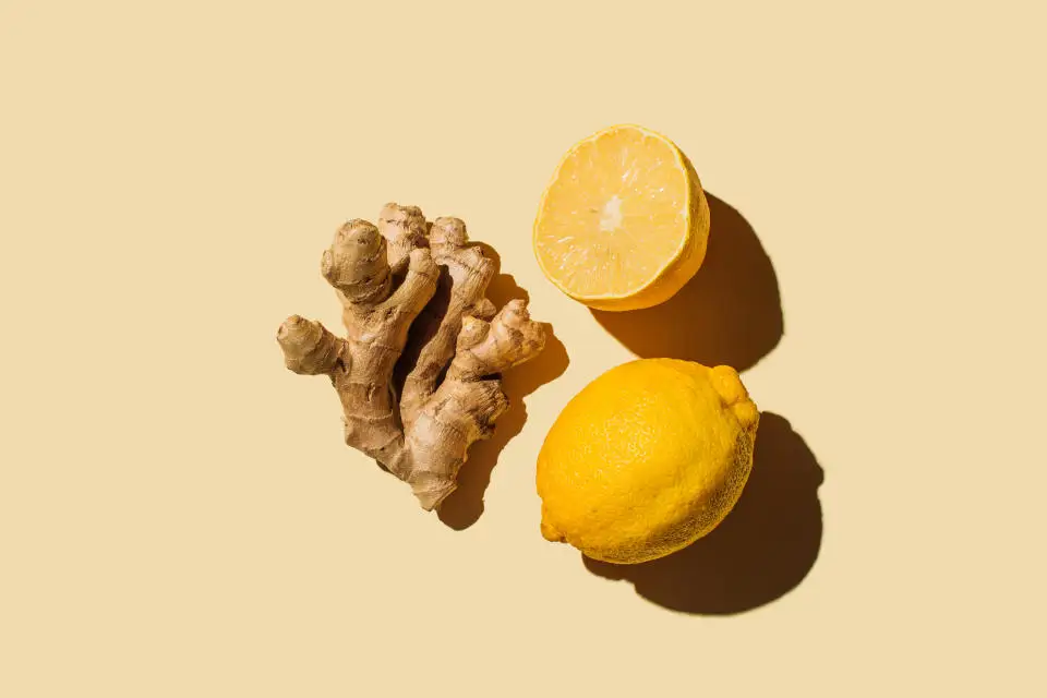 Fresh ginger with lemon on beige background. Flat lay, top view, copy space.