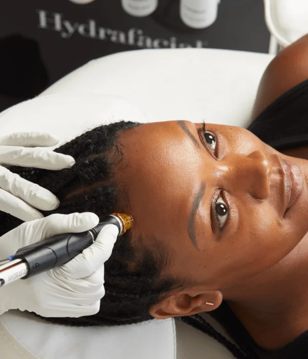 An expert is providing the latest in skincare developments as a person receives a facial treatment with a HydraFacial device while lying on a chair.