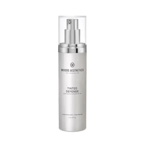 Silver bottle of Woods Aesthetics Tinted Defense cream with a clear cap, showcasing the latest developments in skincare. Expertly formulated with hyaluronic acid and niacinamide.