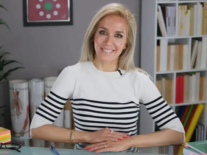 Alex Ruani sits at a desk in a home office, smiling at the camera.