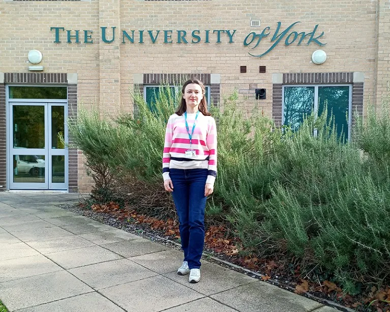 Tetyana Lunyova stands in front of a sign for the University of York