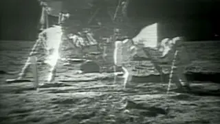 two astronauts in white spacesuits on the moon