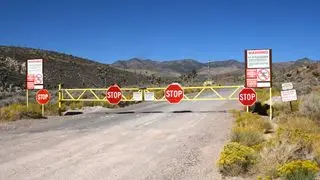 a yellow gate covered in stop signs blocks a road in the desert