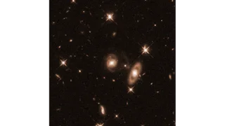 A sepia image of space that shows more context around the header image of this article. There are a few other glowing spots.