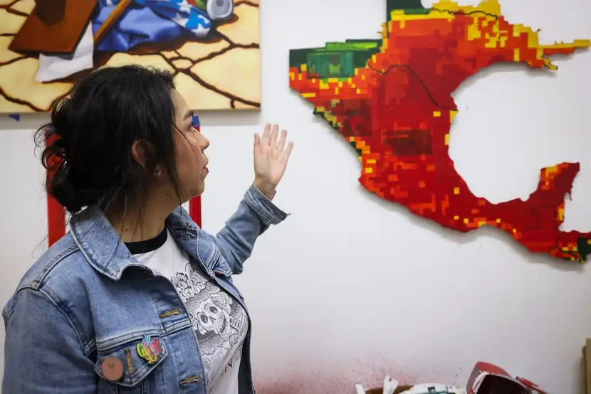 Eliana Miranda points out details on her artwork about immigration and heat-related climate...