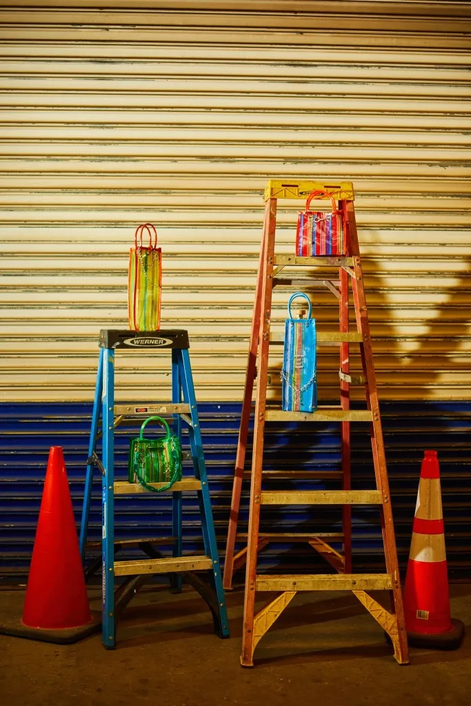 Four Fiera purses sit on two ladders, standing side by side. The ladders are flanked by two orange traffic cones. The display is dark and is setup in front of a closed garage door.