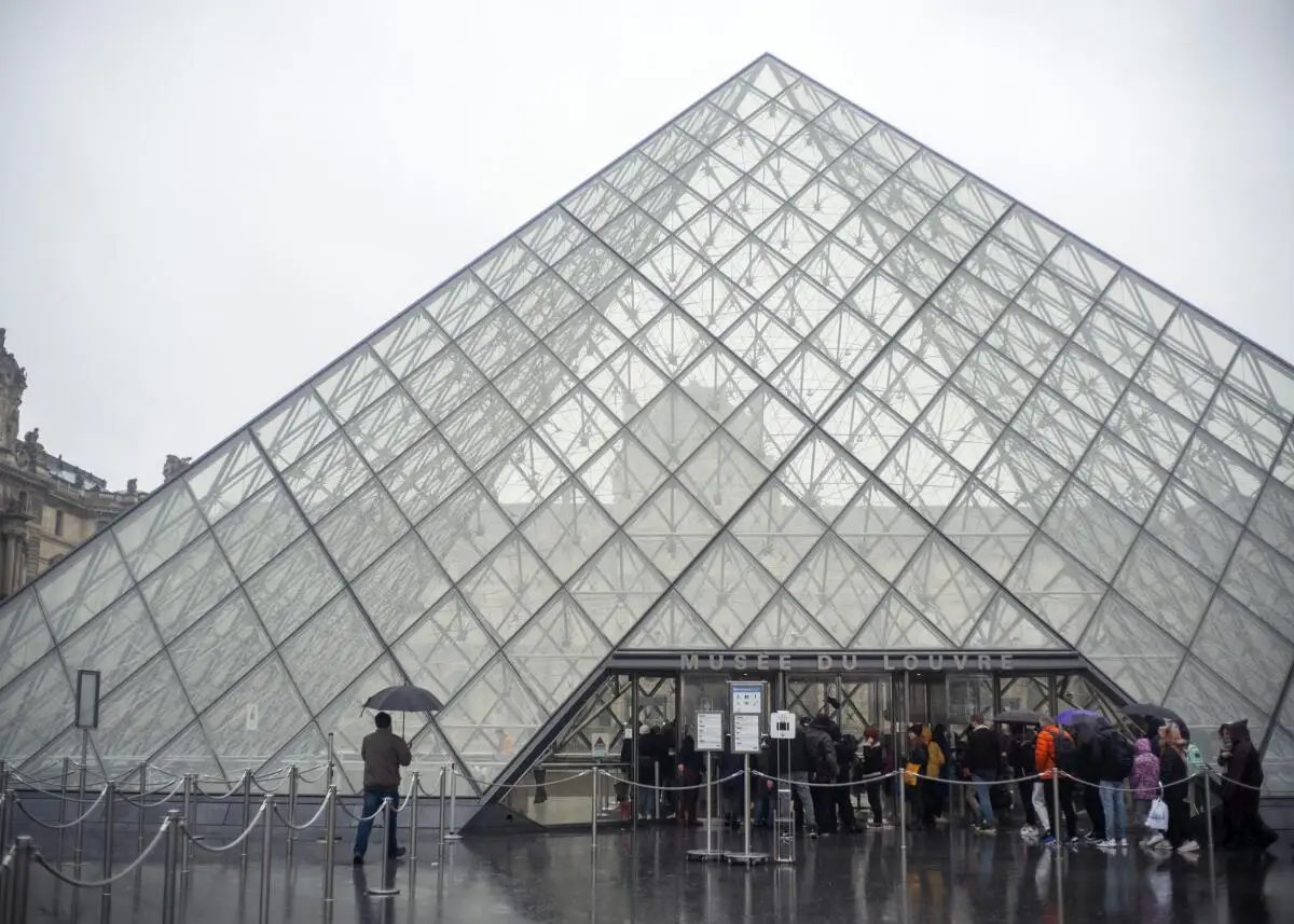 Tourists stand outside the Louvre museum's glass entrance pyramid