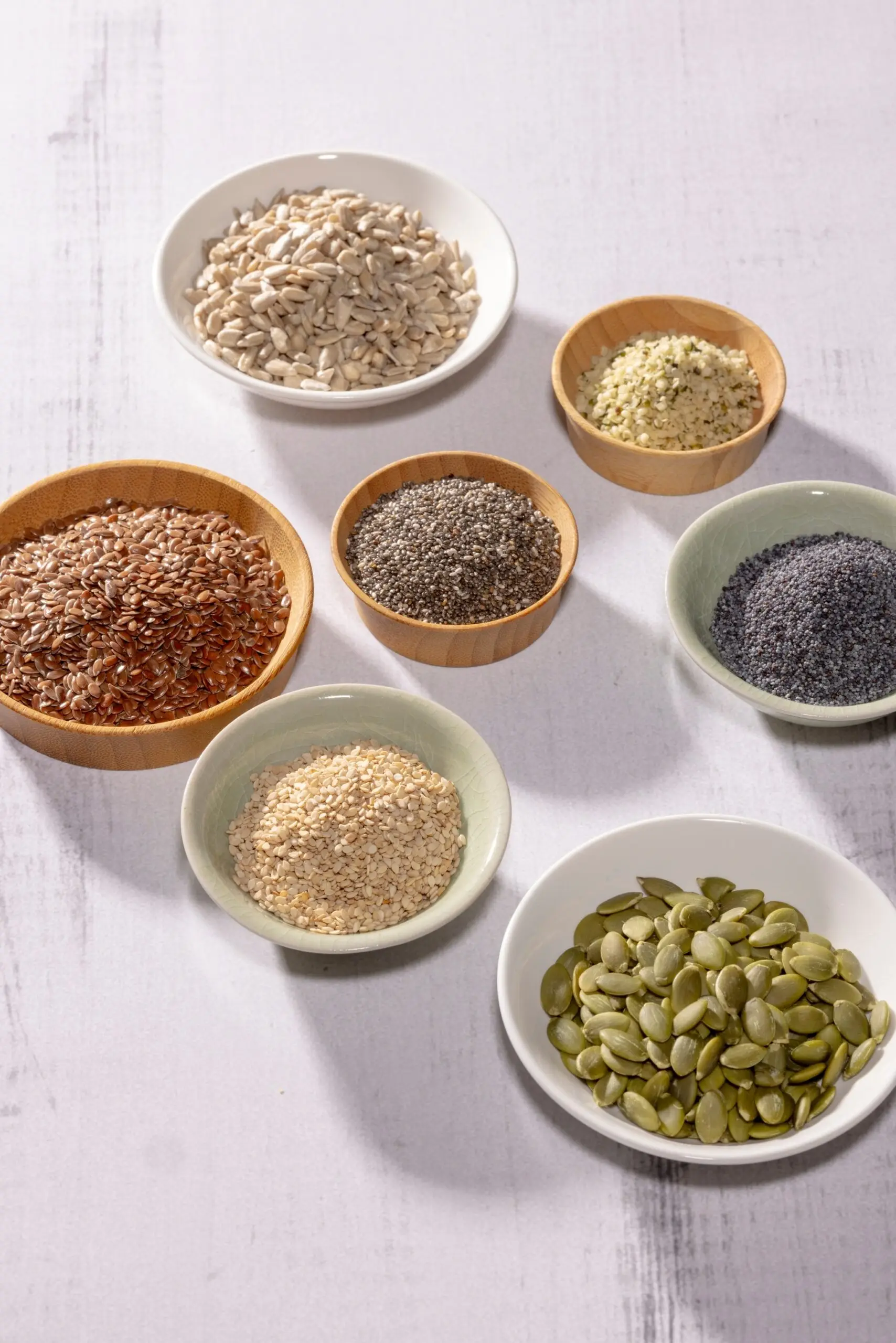 Image of seeds in bowls. Top row: sunflower and hemp seeds. Middle row: Flax, chia, and poppy, seeds. Bottom row: sesame and pumpkin seeds. 