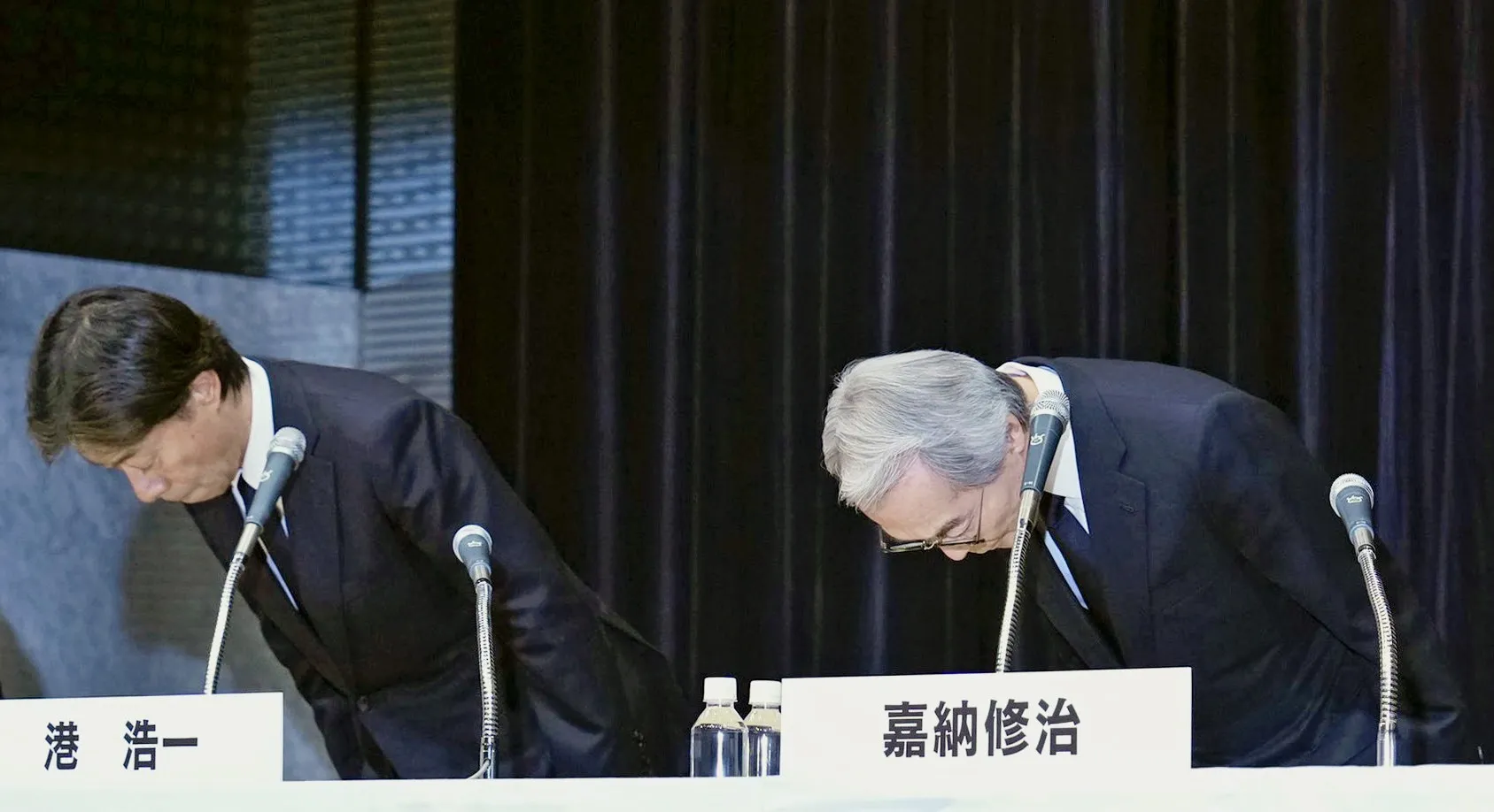 Three Fuji Television Network executives bowing at a press conference.