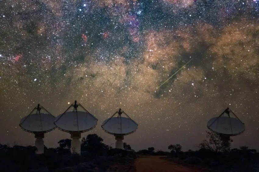 4 radio dishes pointed towards the night sky, which is covered in a blanket of stars