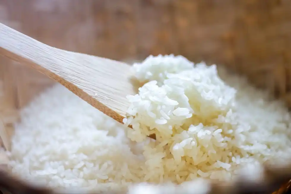 close up of white rice being scooped up with rice paddle