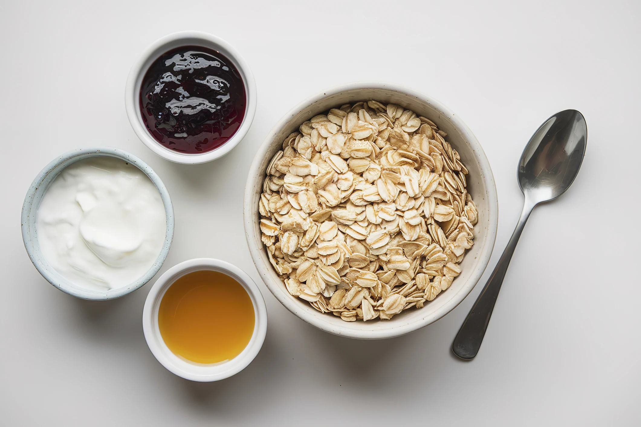 Dry oats served with yogurt, jam, and honey.