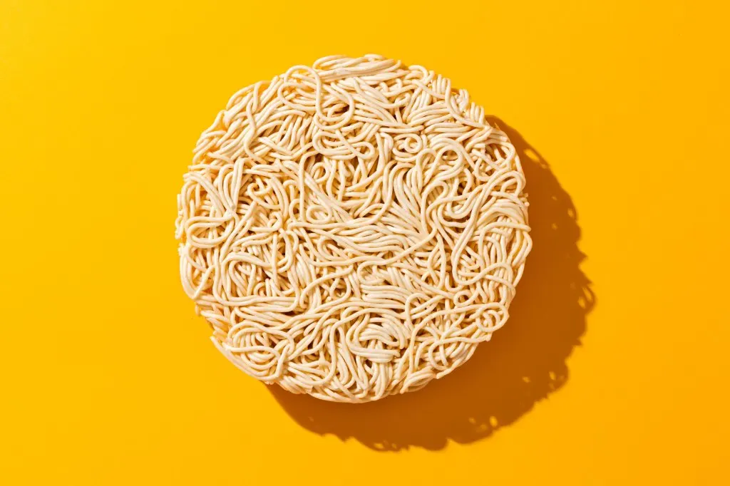 dry uncooked instant ramen noodles on yellow background