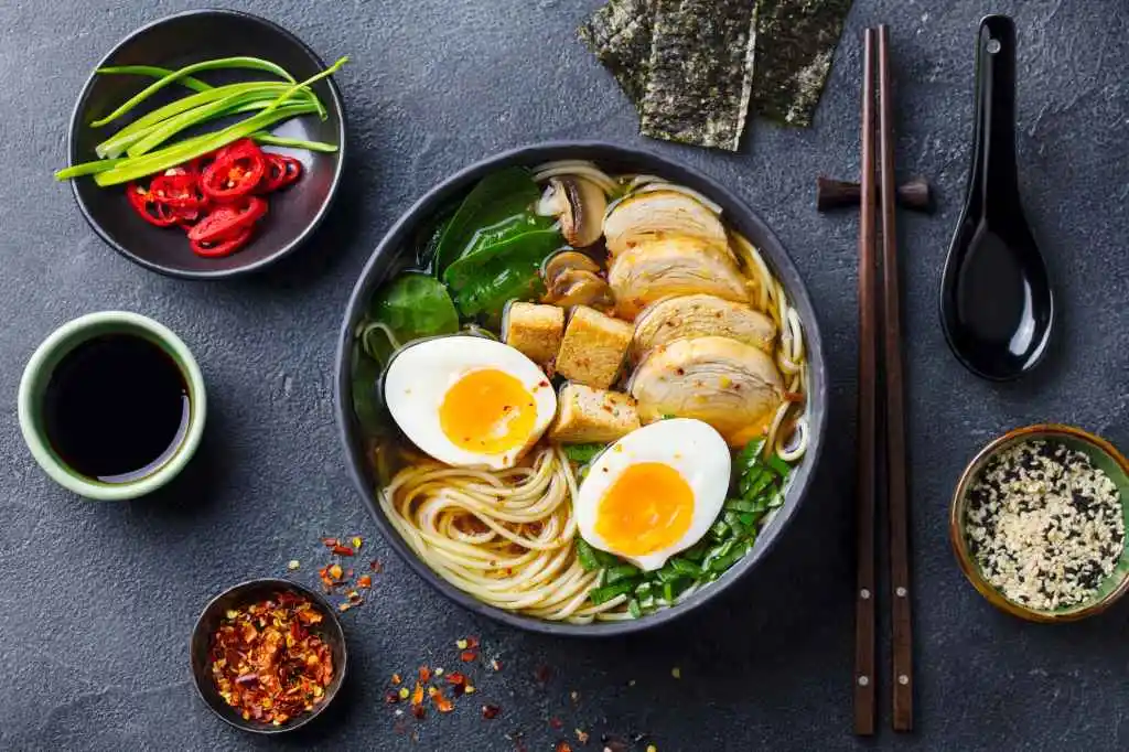 Asian noodle soup, ramen with chicken, tofu, vegetables and egg in black bowl