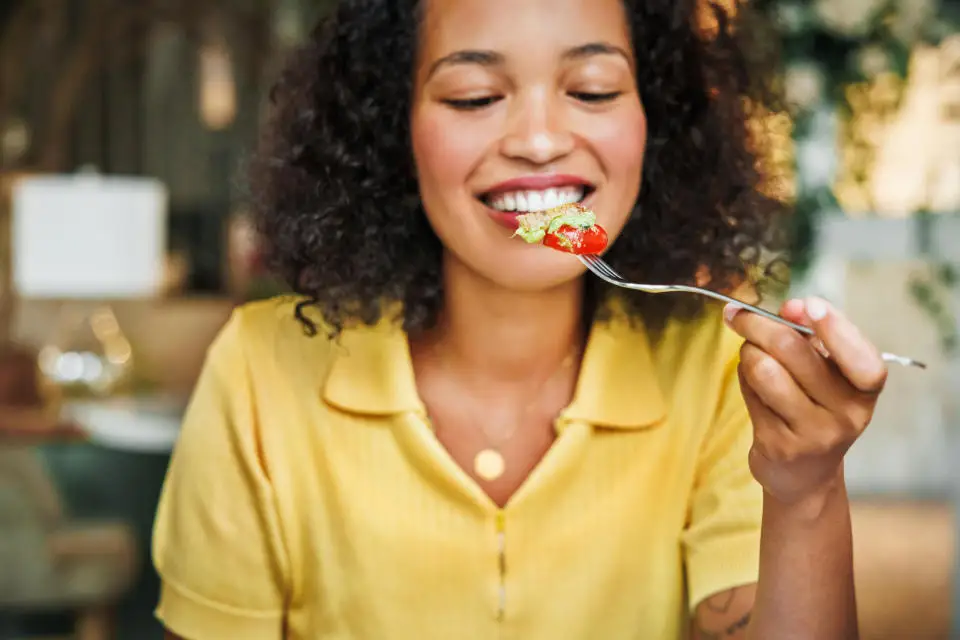 A joyful woman is about to enjoy a bite of a fresh and appetizing salad, highlighting the pleasures of healthy eating.