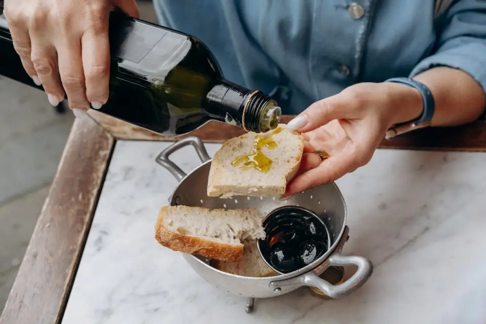 women's hands with traditional antipasti in a local Italian restaurant fresh bread with organic olives and local fresh olive oil