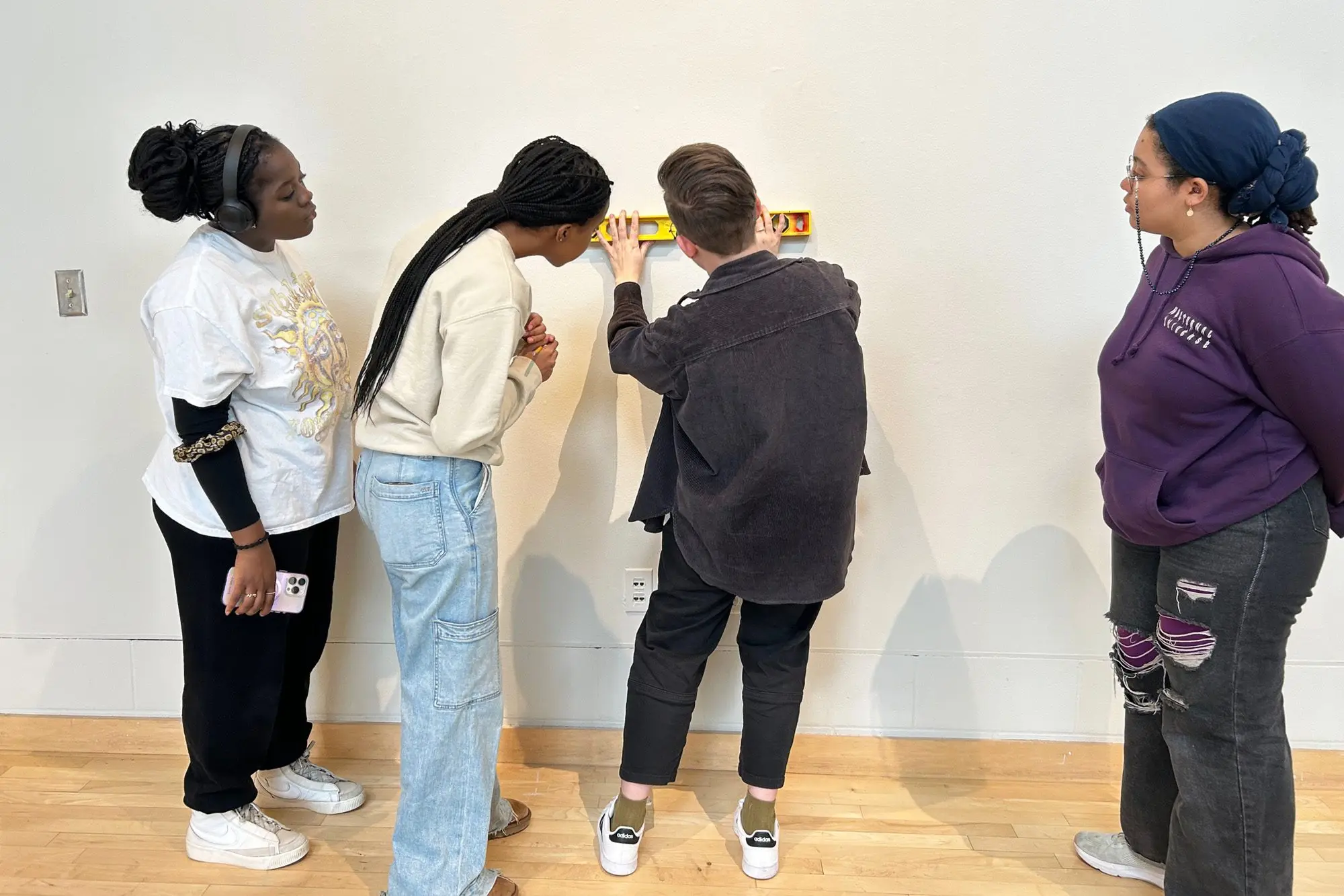 Curators of this year's UPRISING exhibit work on the installation of the pieces with support from Flaten Art Museum Collections Manager Krista Anderson-Larson. Photo by Flaten Art Museum Director Jane Becker Nelson '04