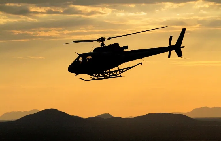 The silhouette of a helicopter during a geophysical mineral survey in Namibia.