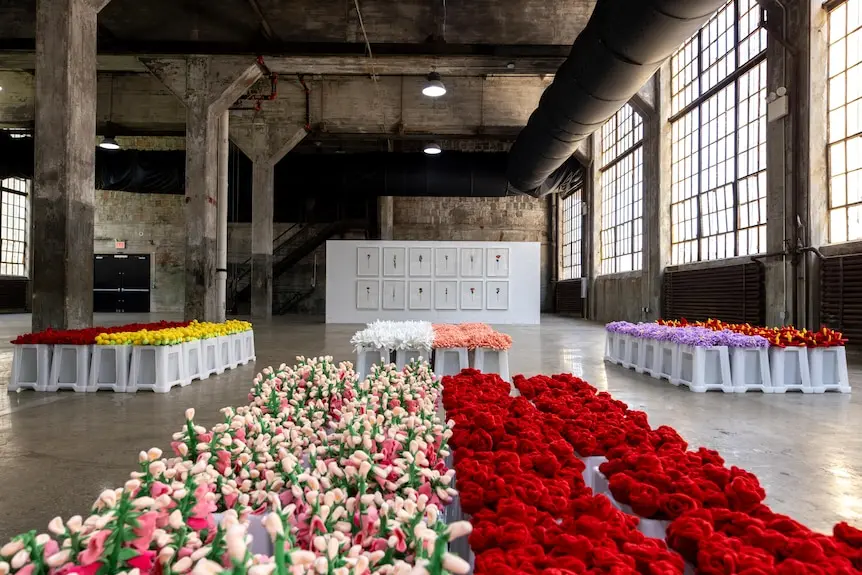 Large warehouse with many neatly displayed red, pink and white flowers.