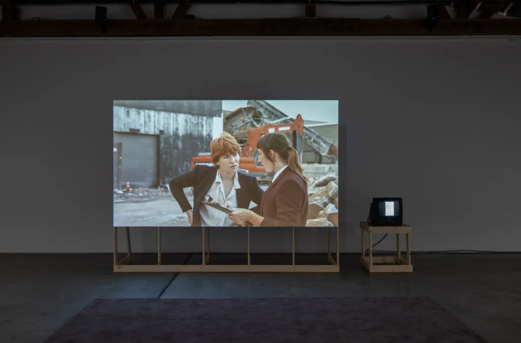 two screens in a gallery space - one projection screen and the other a small CRT television