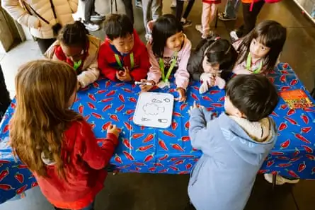 Students crowd around a table and look at a whiteboard with drawings of food ingredients