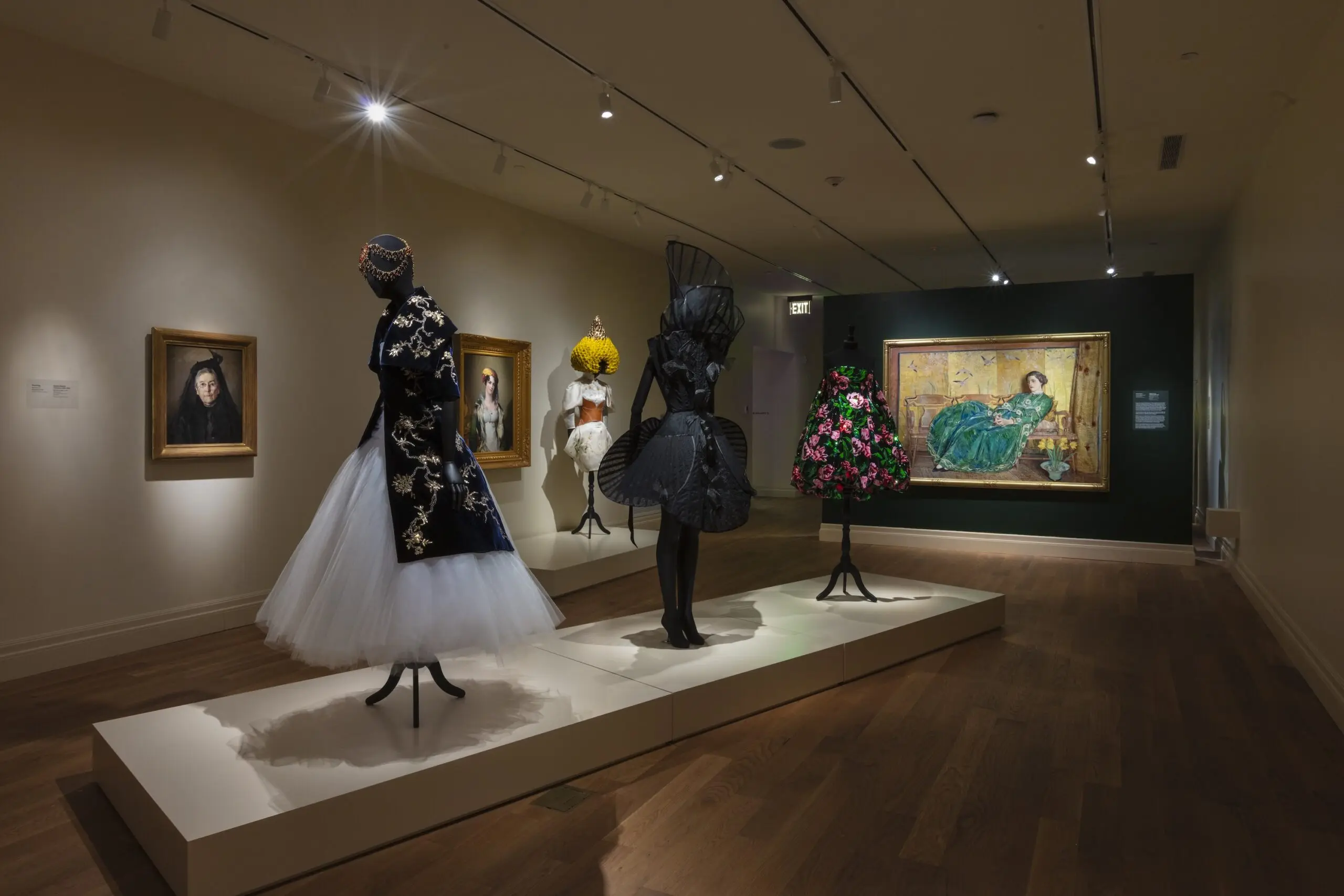 A display of a museum exhibit with stunning high fashion designs paired with paintings