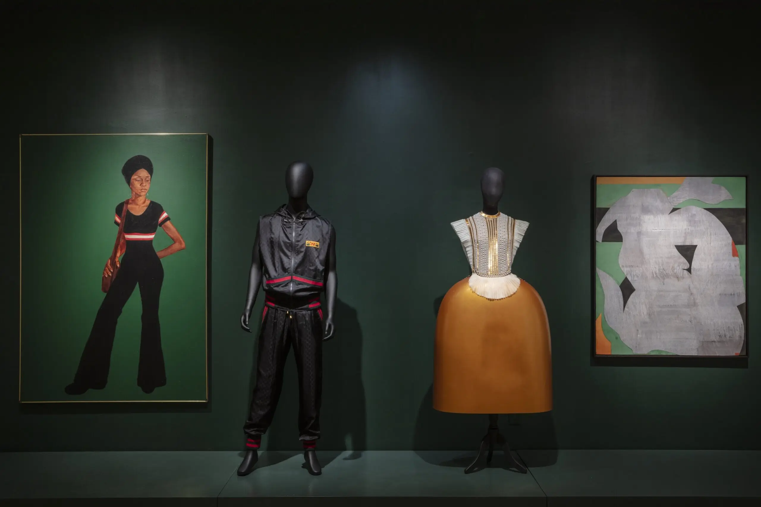 An installation view of a tracksuit and a portrait of a woman and a hard skirt-dress with an abstract painting