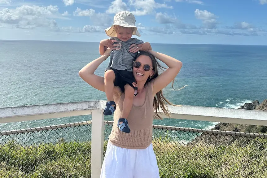 A woman has her toddler son sitting on her shoulders.