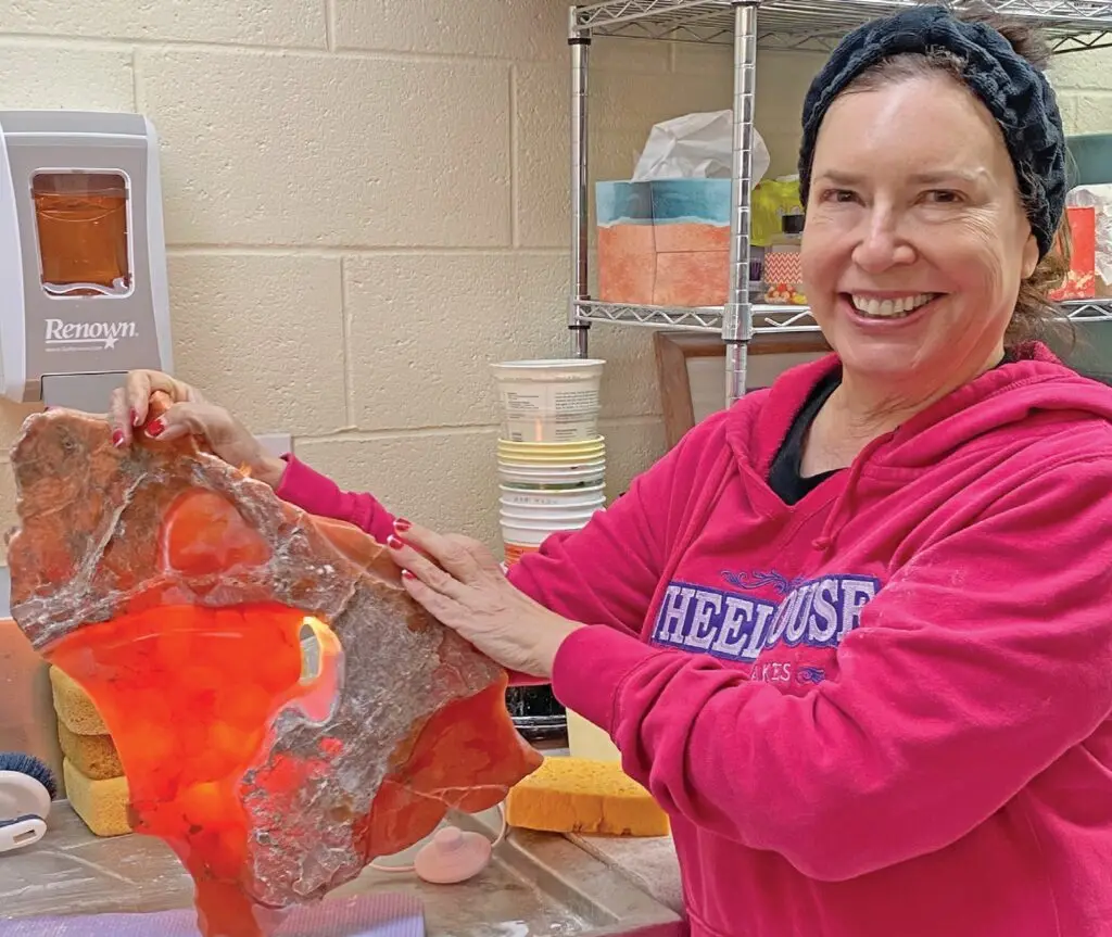 Marcie Karavakis shows off the piece of Red Utah alabaster she is working with in the stone sculpting studio that shines translucent in the light. MARY WOZNIAK / FLORIDA WEEKLY