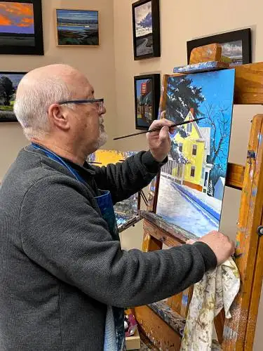 Northfield Mount Hermon art teacher Bill Roberts paints a yellow house in the snow.