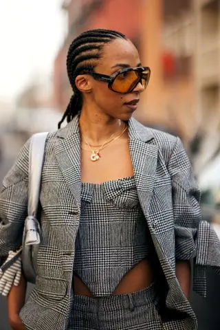 woman with cornrows, glasses, and a gray suit