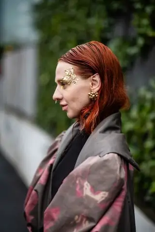 woman with red hair and gold face paint