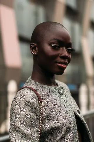 woman in a silver Gucci jacket with lots of earrings and silver eyeliner