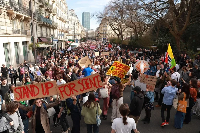 An elevated view of a large crowd of sign waving people filling a street during a 'Stand up for Science' march.