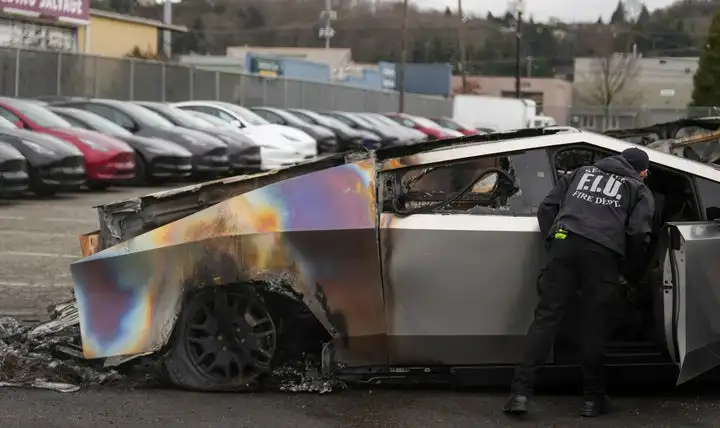 A member of the Seattle Fire Department inspects a burned Tesla Cybertruck at a Tesla lot in Seattle, Monday, March 10, 2025. (AP Photo/Lindsey Wasson)