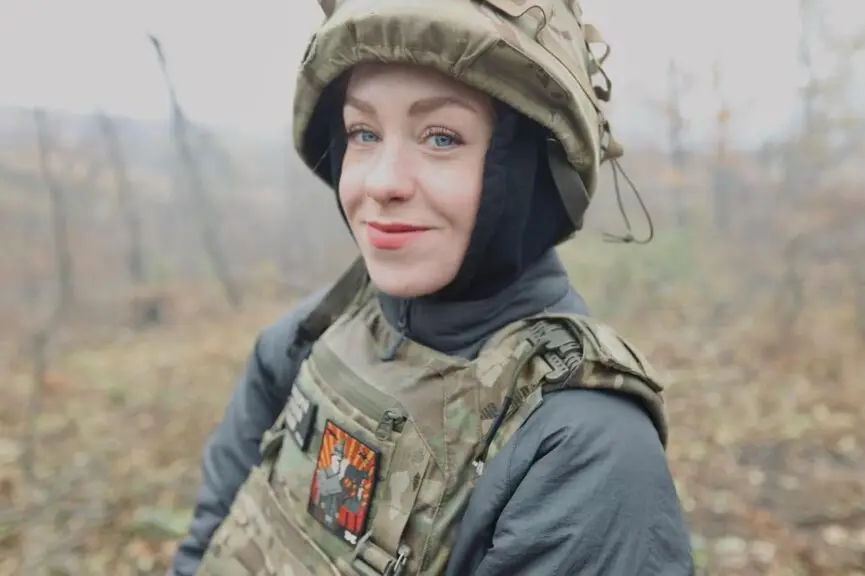 Nathalie Vlasenko, a young white woman stood outdoors wearing combat uniform.