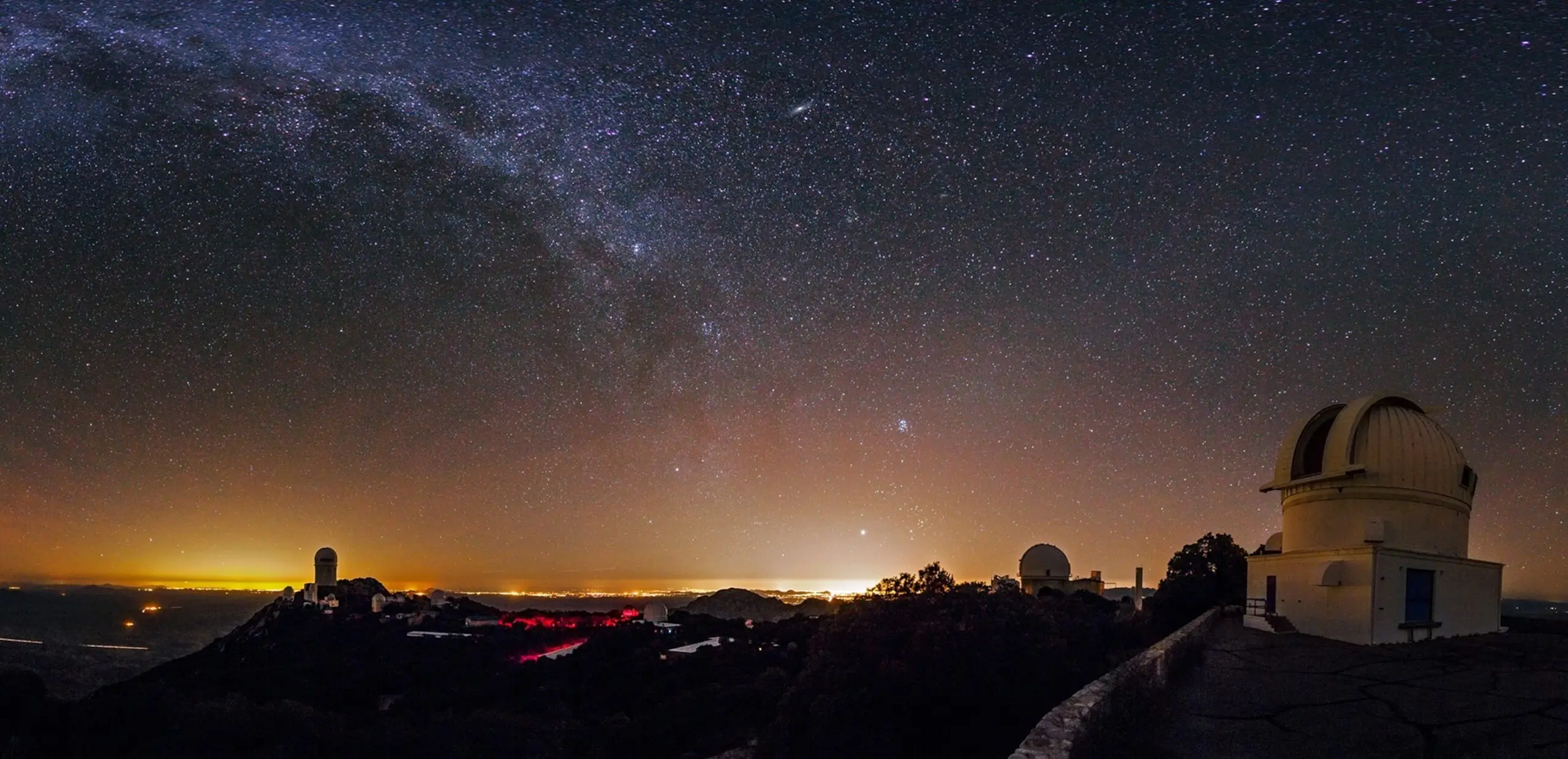 The night sky and the Milky Way above Kitt Peak Observatory. Tucson is on the right, and Phoenix is on the left. The WIYN 0.9 meter telescope is close in the foreground.