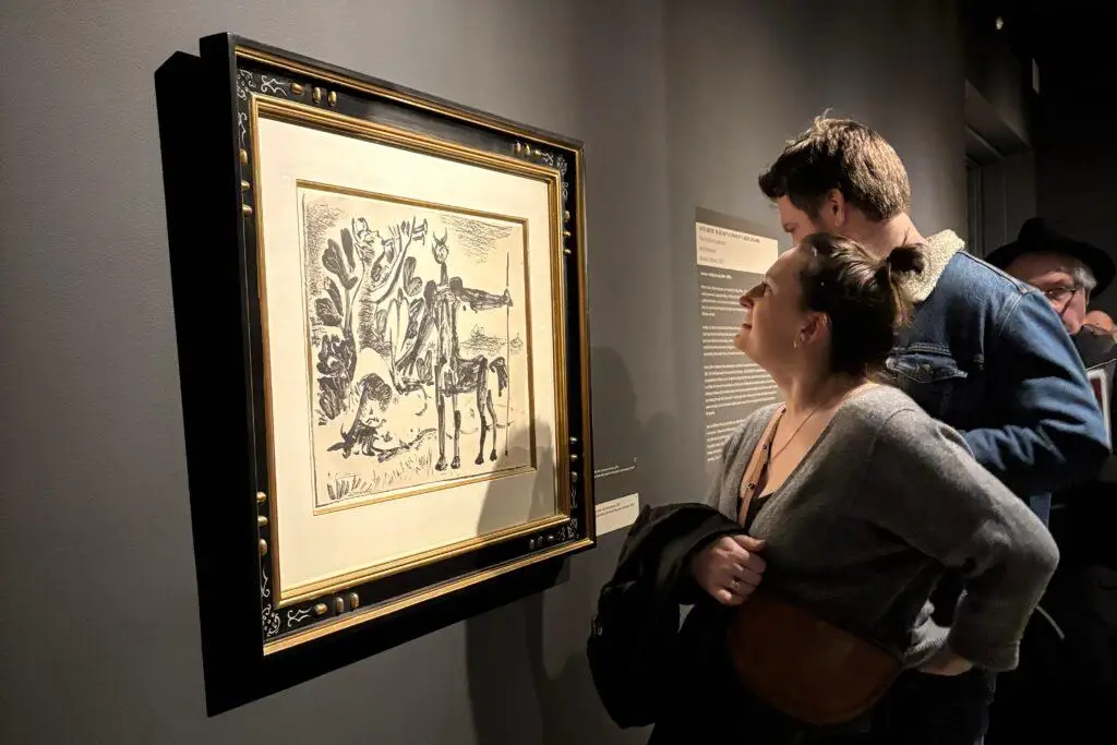 A woman smiles as she looks at a black and white Picasso work hanging on the wall of the Longmont Museum.