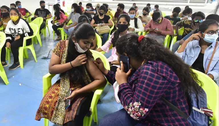 A woman checks the inoculation point of her friend after getting the Covid-19 vaccine during a vaccination drive in India.