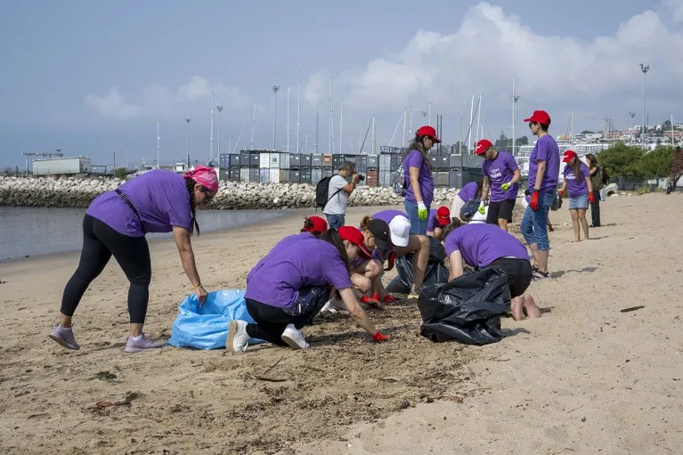 Several volunteers collect waste and garbage in bags during a beach cleanup day in Lisbon, Portugal.