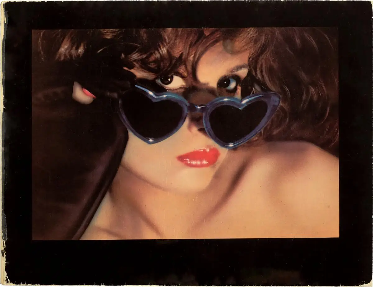A photo of a woman lowering her heart-shaped sunglasses in a seductive manner