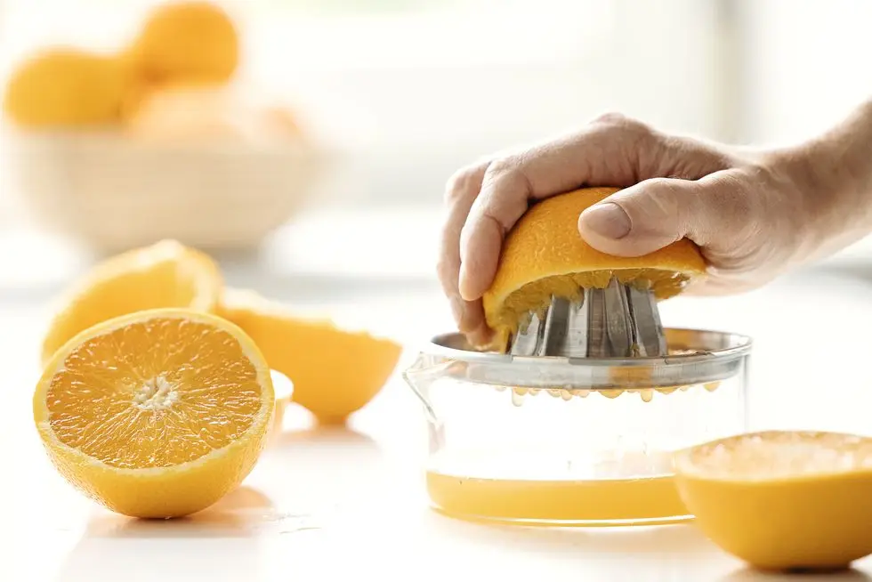 man squeezing oranges with juicer