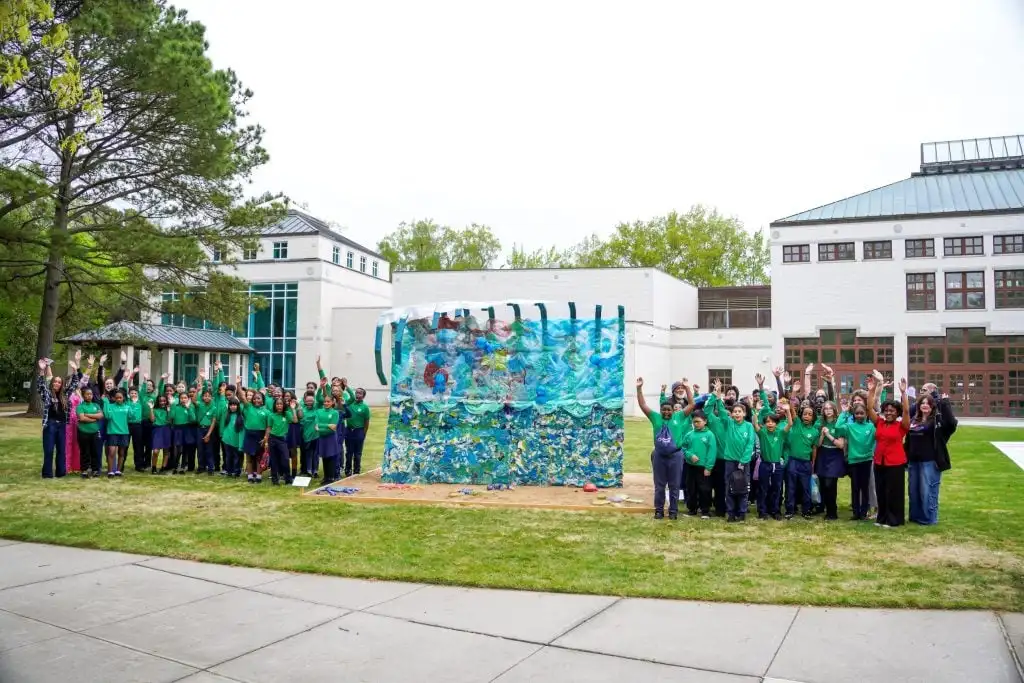 Groups of school children stand with colorful artworks outside the Virginia Museum of Contemporary Art