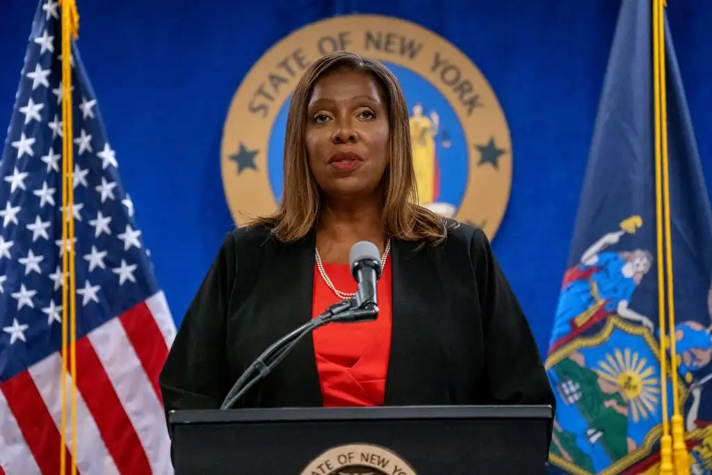 New York Attorney General Letitia James speaking at a podium, with state and U.S. flags.