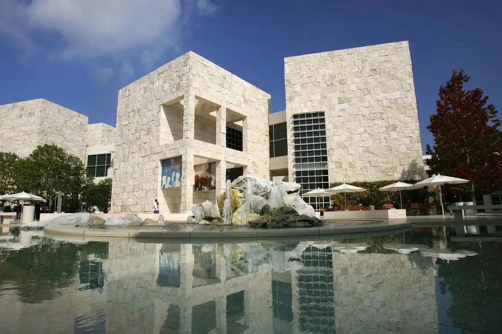 The Getty Center’s modern stone architecture, reflecting pool, and outdoor seating under a clear blue sky.