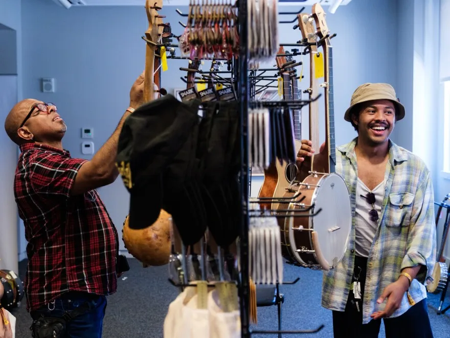 Former Carolina Chocolate Drops member Rowan Corbett (left) and a shopper look at banjos inside a pop-up shop at the festival.