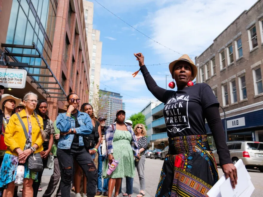 Aya Shabu, founder of Whistle Stop Tours, guides a group of festival attendees on a walking tour of Durham's Black Wall Street as part of the Biscuits & Banjos programming.