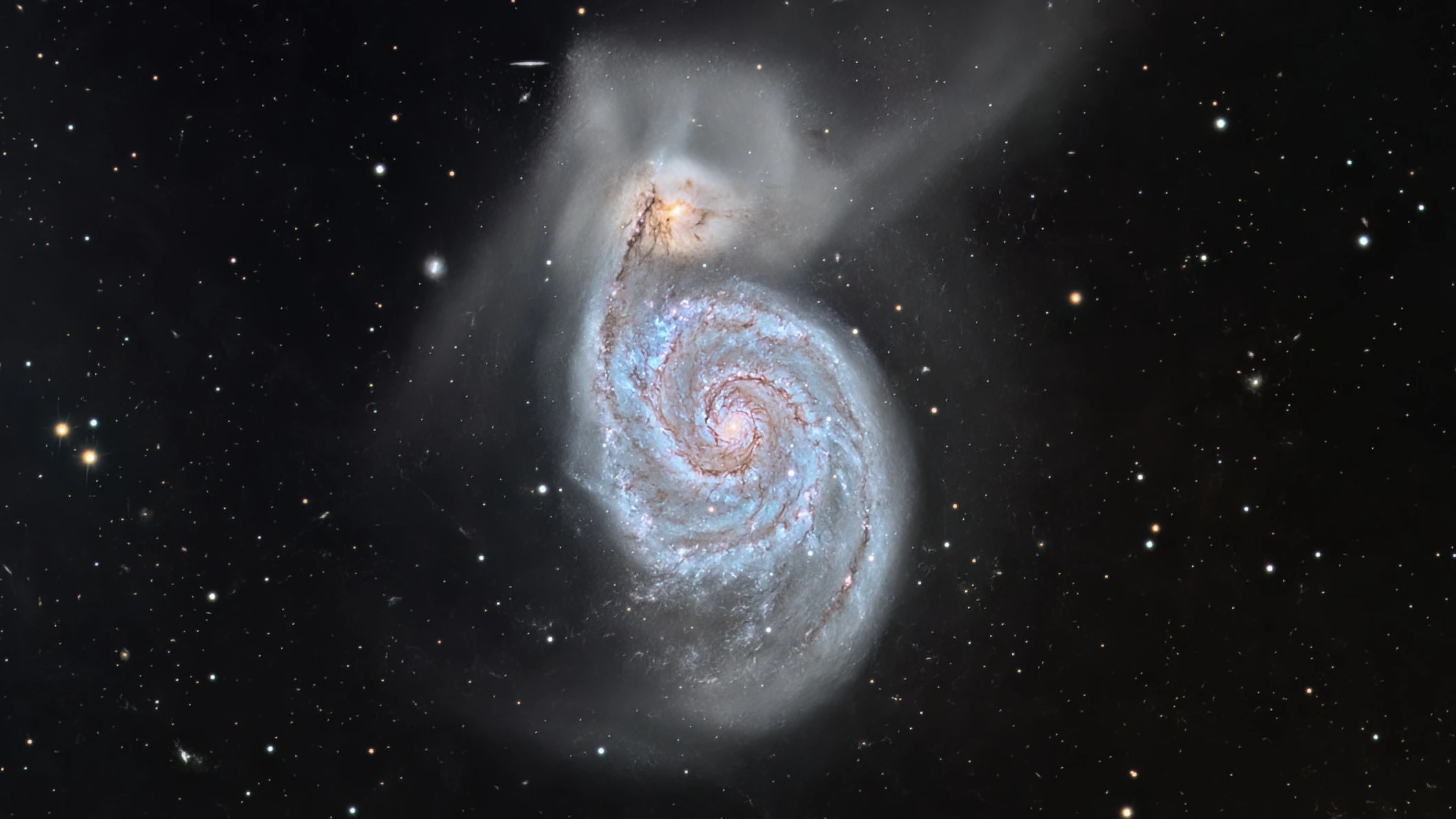a wispy white spiral seen in front of hundreds of background stars
