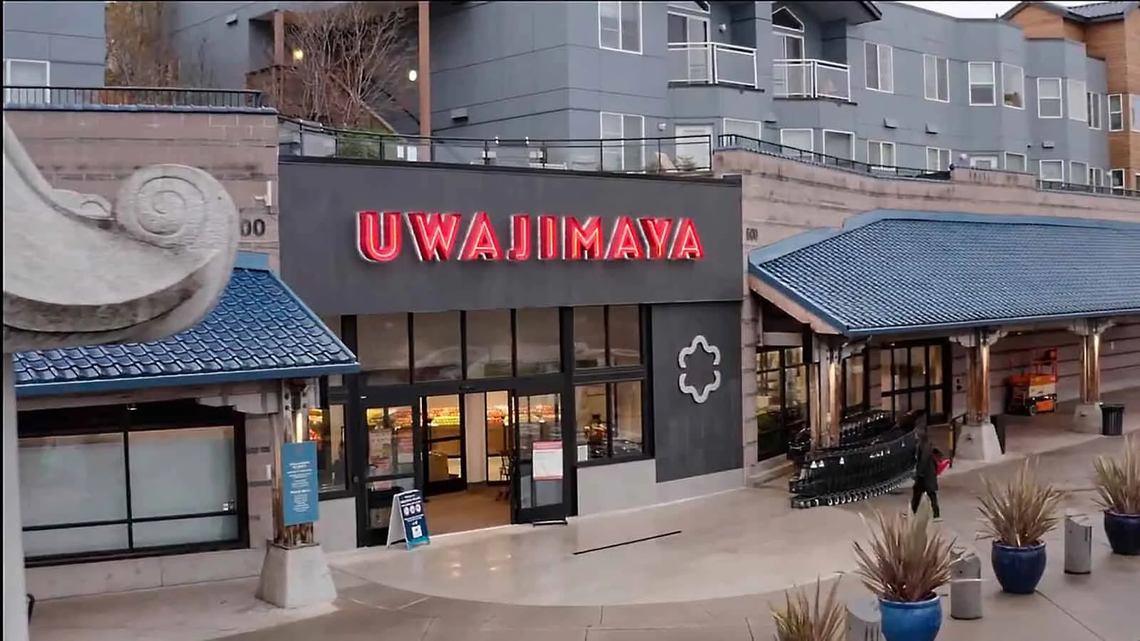 Exterior view of Uwajimaya store with large red sign, glass doors, and shopping carts outside, located beneath apartment buildings—capturing the vibrant spirit of Sound To Summit: AANHPI Voices Rising in Seattle.